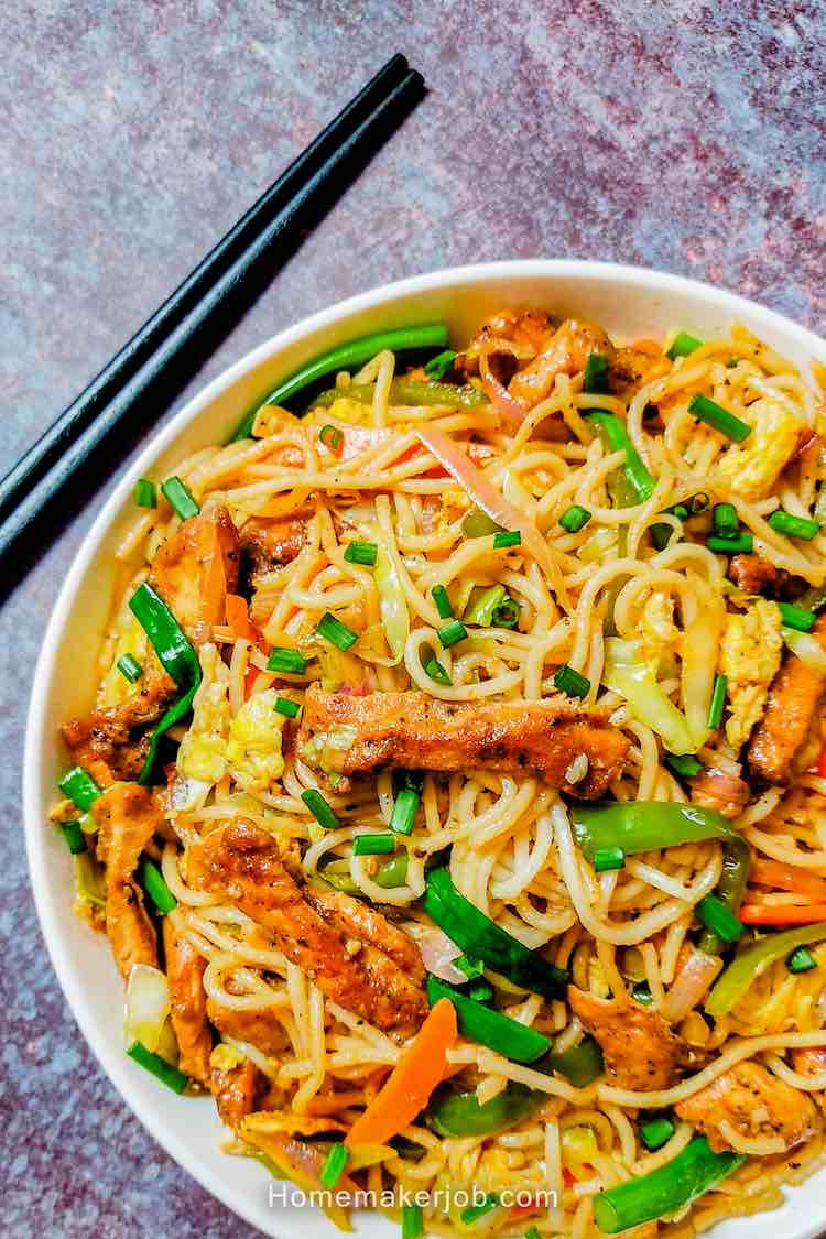 Ready chicken hakka noodles served hot in white bowl accompanied with two black chopsticks