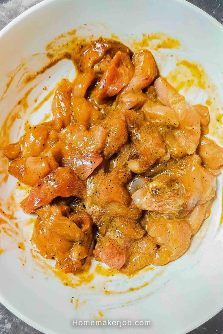 Marinating the chicken in a white bowl to make chicken hakka noodles