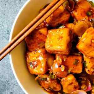 Chilli Paneer served in a white dish with two chopsticks kept on dish, by homemakerjob.com