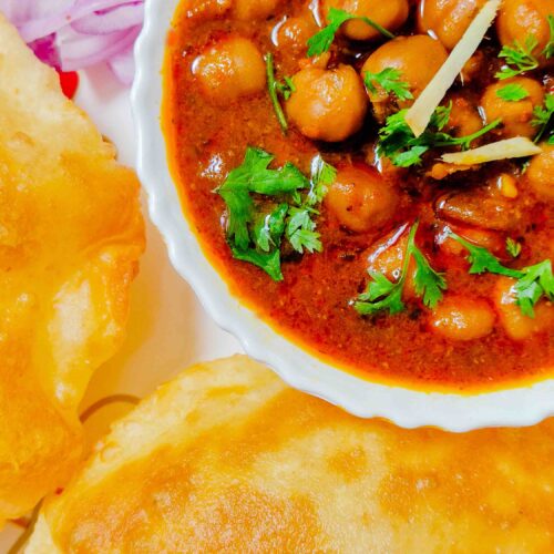 Chhole served hot with bhature and red onions in a white dish, by homemakerjob.com