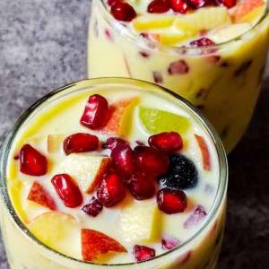 Tasty light yellow colored in a two glasses garnished with pomegranate seeds at top, put on a table, a recipe by homemakerjob.com