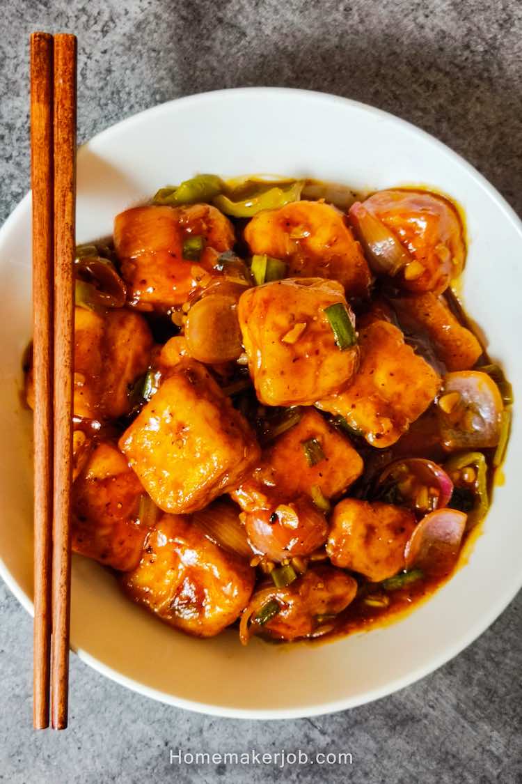 Chilli Paneer served in a white dish with two chopsticks kept on dish, by homemakerjob.com