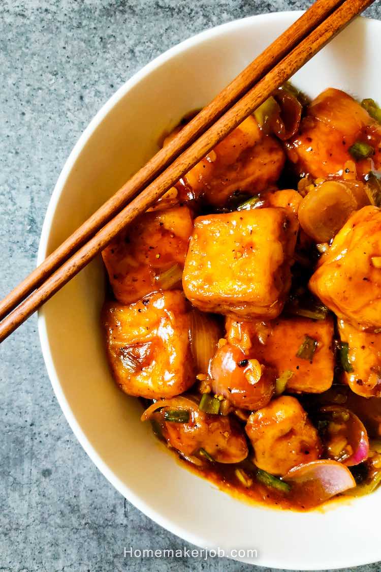 Chilli Paneer served in a white dish with two chopsticks kept on dish, by homemakerjob.com