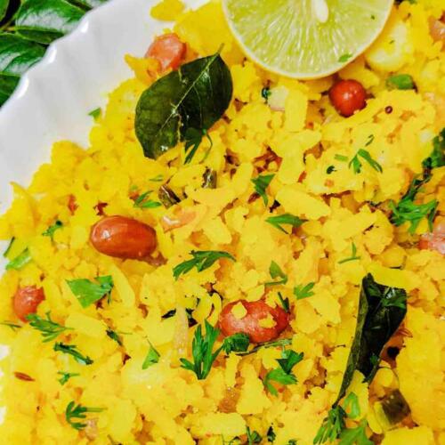 Tasty Poha served hot with half lime slice in a white dish, by homemakerjob.com
