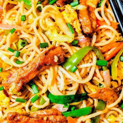 Chicken Hakka Noodles served hot in a white dish with two black chopsticks