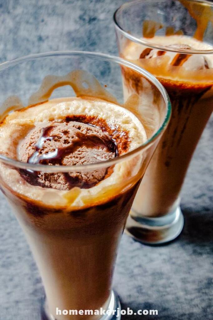 Two tall glasses filled with chilled chocolate milkshake and ice-cream on top
