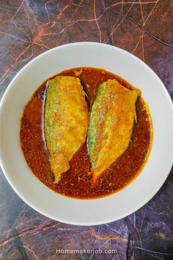 Two fillets of bangda (ayala) fish in hot spicy red curry, served in a white dish by homemakerjob.com