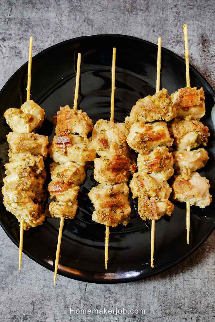 Ready malai chicken tikka served in a black plate with green chutney by homemakerjob