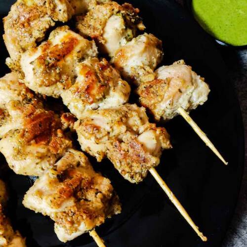 Close up photo of Ready chicken malai tikka served in a black plate with green chutney by homemakerjob