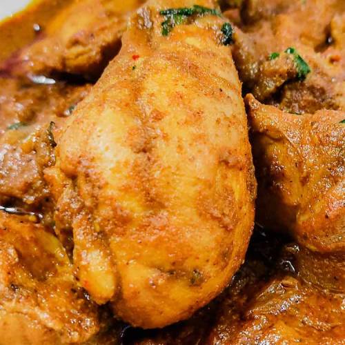 Close up photo of ready hot chettinad chicken gravy served in a white plate on a table by homemakerjob.com