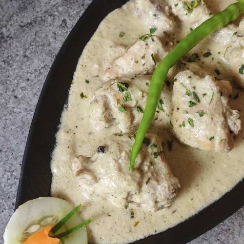 Close up photo of ready white chicken gravy garnished with coriander & green chili, decorated with cucumber & carrot, served in a black plate by homemakerjob.com