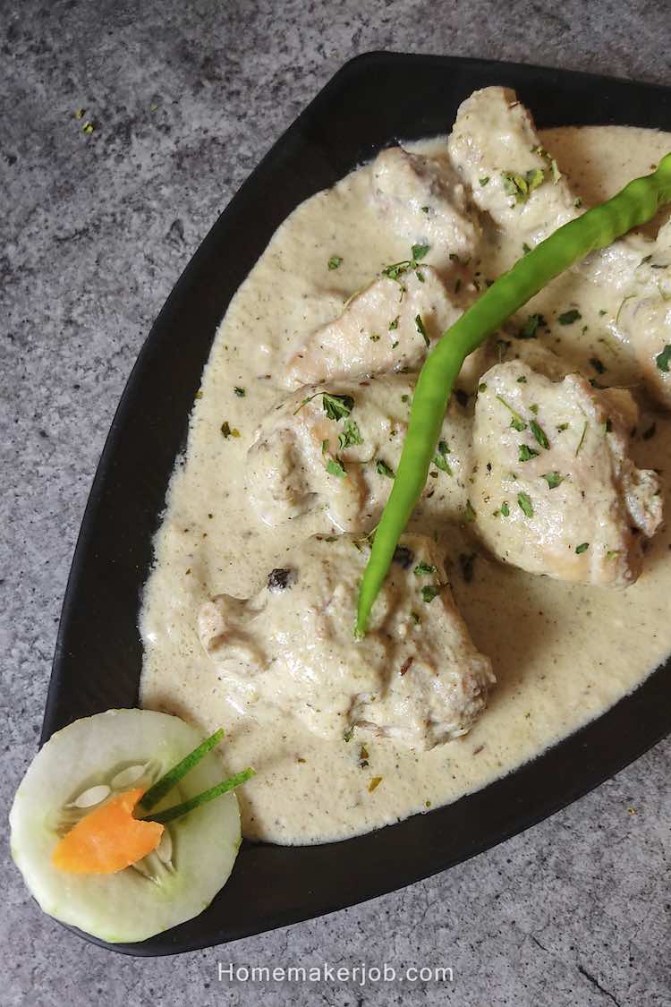 Close up photo of ready white chicken gravy garnished with coriander & green chili, decorated with cucumber & carrot, served in a black plate by homemakerjob.com