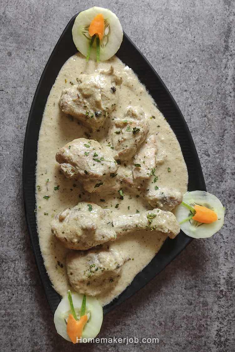 Photo of ready white chicken gravy garnished with coriander, decorated with cucumber & carrot, served in a black plate by homemakerjob.com