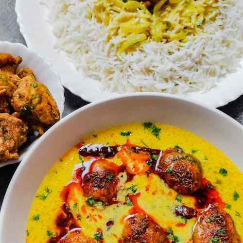 Close up photo of ready punjabi kadhi pakoda served with pakoras by homemakerjob.com