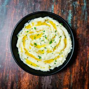 Ready creamy butter garlic mashed potatoes served hot in a black dish on a table by homemakerjob