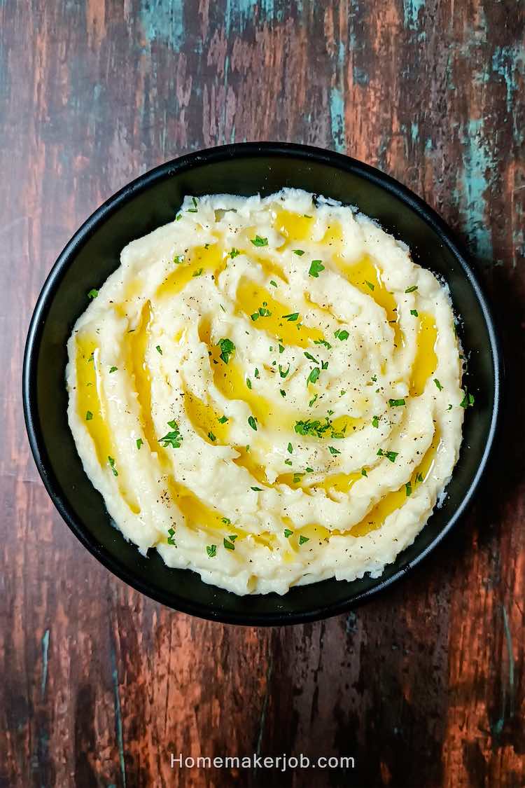 Photo of ready creamy butter garlic mashed potatoes served hot in a black dish on a table by homemakerjob