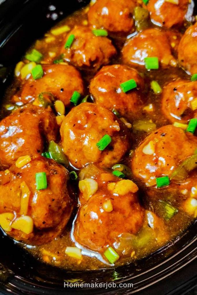 Close up photo of ready restaurant style chicken manchurian gravy served in a black plate on a table, by homemakerjob.com