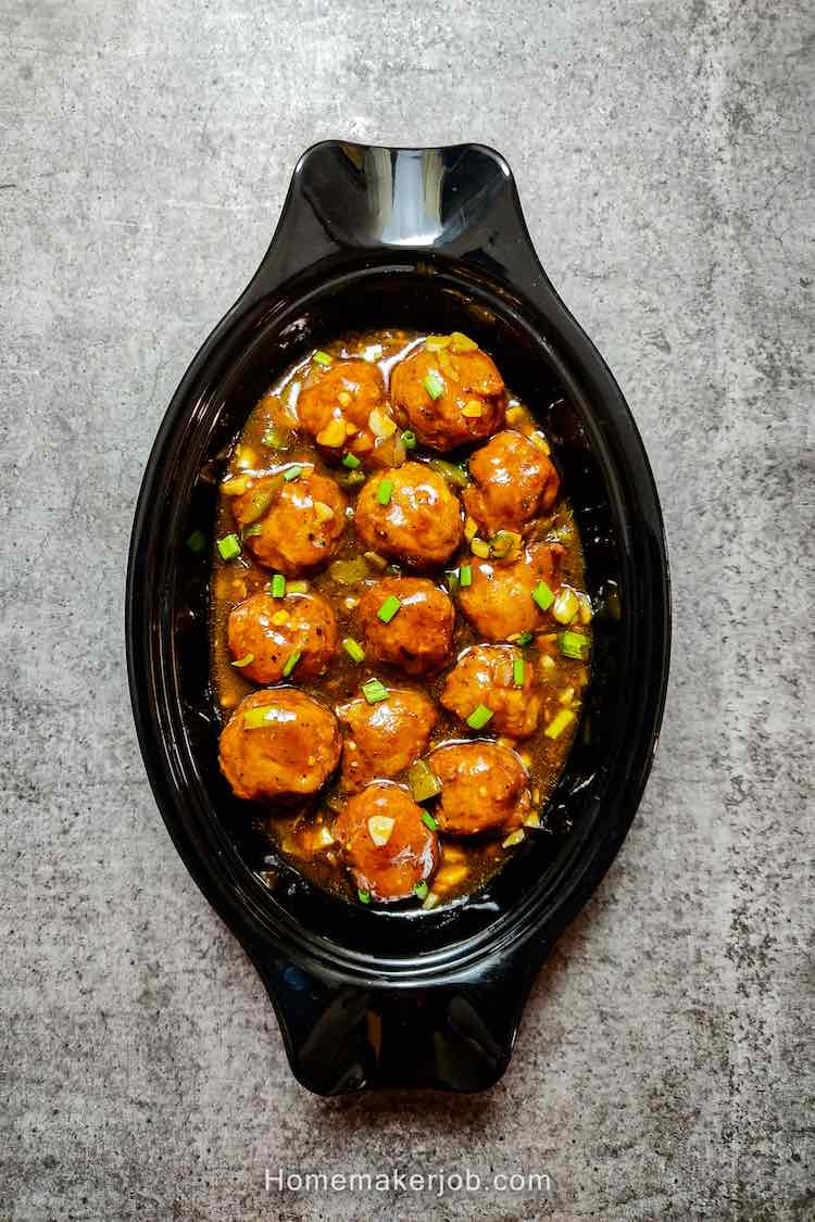 photo of ready restaurant style chicken manchurian gravy served in a black plate on a table, by homemakerjob.com