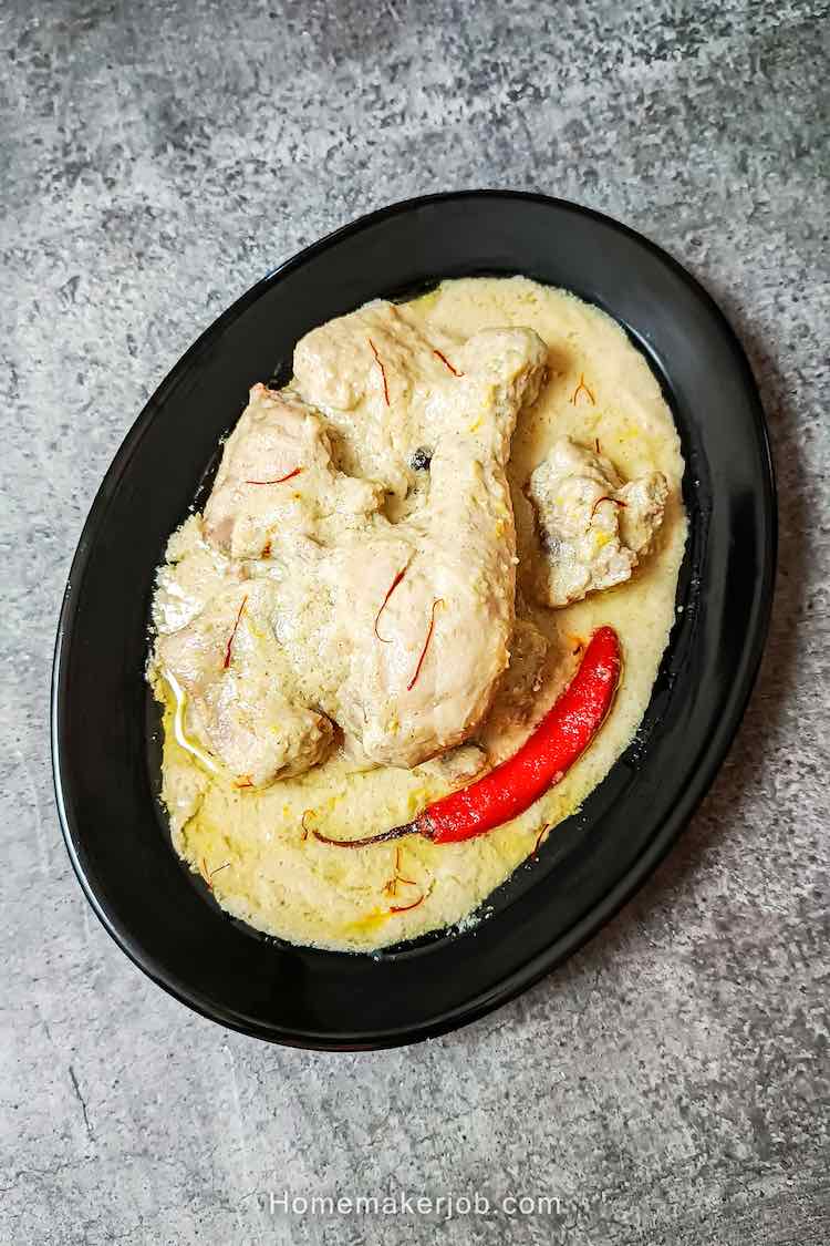 Best chicken rezala curry garnished with red chili, served hot in a black plate on table top, by homemakerjob.com