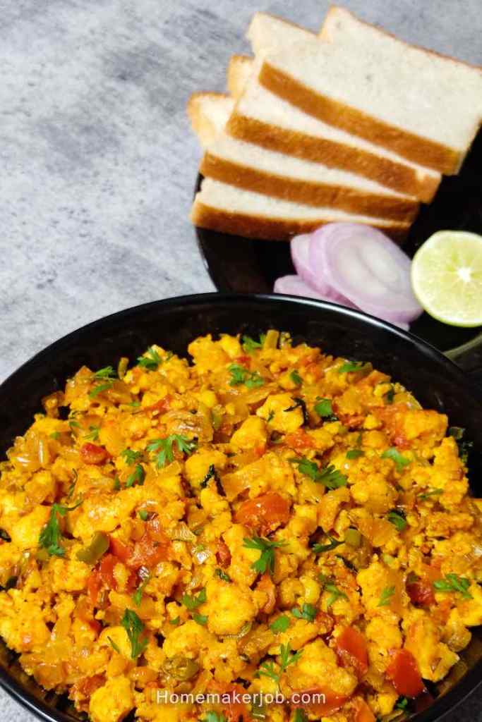 Ready hot restaurant style paneer bhurji dry served in a black with white breads garnished with onion and lemon slices, by homemakerjob