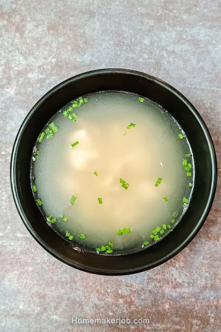 Hot chinese chicken clear soup served in a black bowl, by homemakerjob