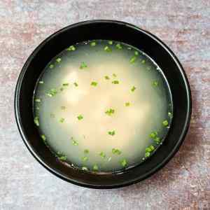 Hot chinese chicken clear soup served in a black bowl, by homemakerjob