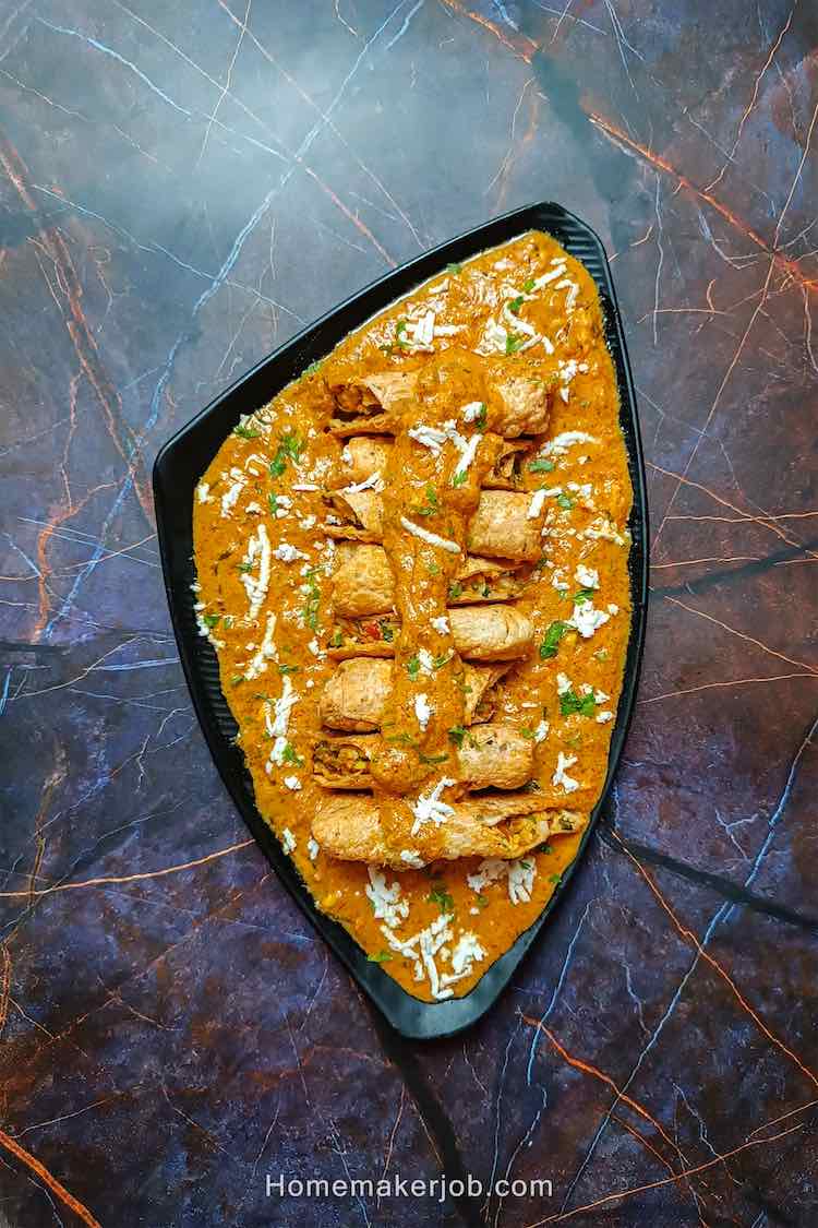 Paneer patiala garnished with cottage cheese and served in a black dish on a table top, by homemakerjob