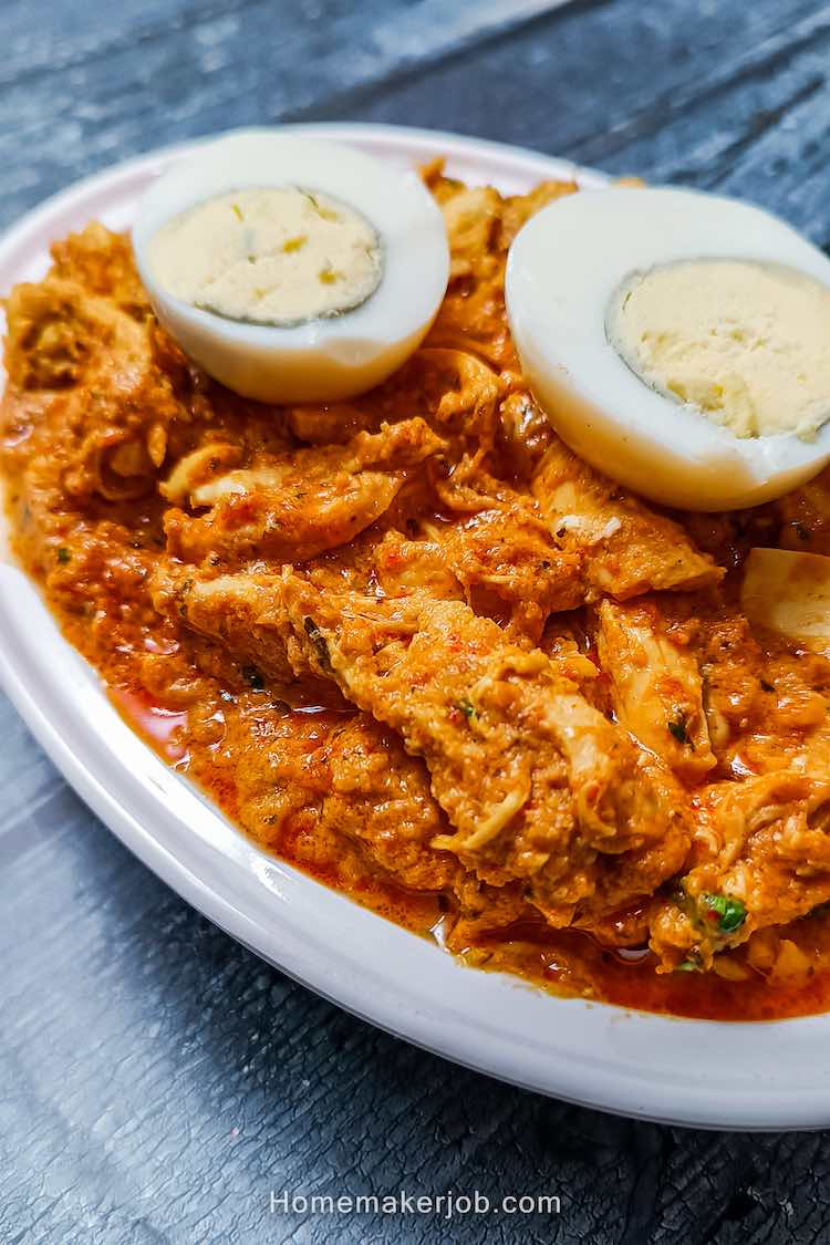 Close up top side view photo of chicken bharta in a white bowl, garnished with two halves of cut egg on top, a recipe by homemakerjob.com