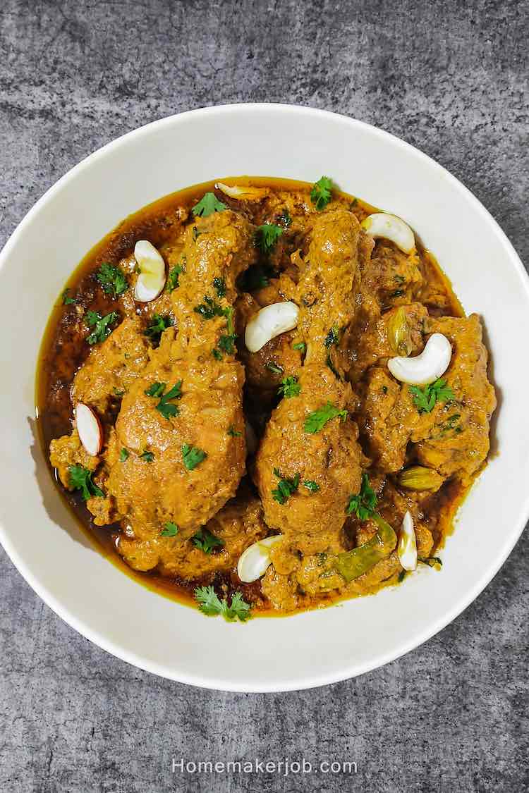 Chicken mughlai garnished with cashews and chopped coriander leaves on top, served hot in a white bowl, a recipe by homemakerjob