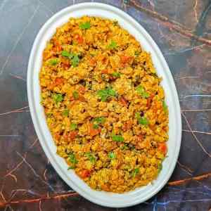 Egg bhurji served hot in a oval shaped white dish on a table top by homemakerjob.com