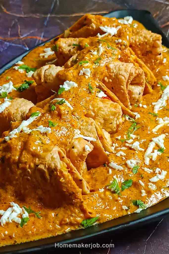 Close up photo of paneer patiala garnished with cottage cheese and served in a black dish on a table top, by homemakerjob