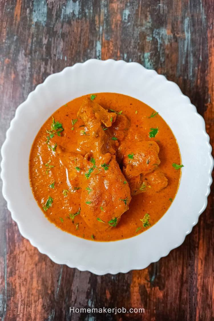 Top view photo of ready chicken lababdar served hot in a white bowl on a table top, by homemakerjob.com