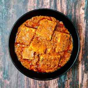 Achari paneer masala in a black bowl on a table top, a recipe by homemakerjob