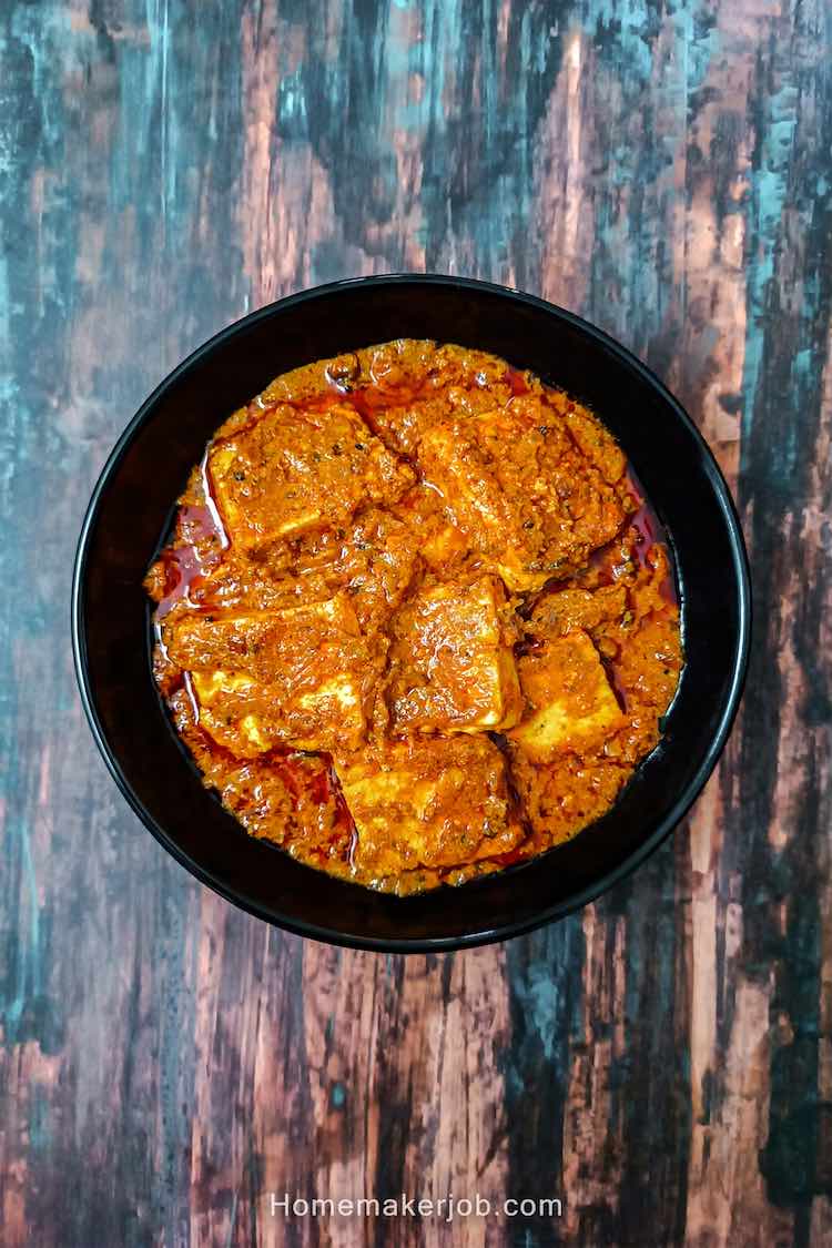 Achari paneer masala in a black bowl on a table top, a recipe by homemakerjob