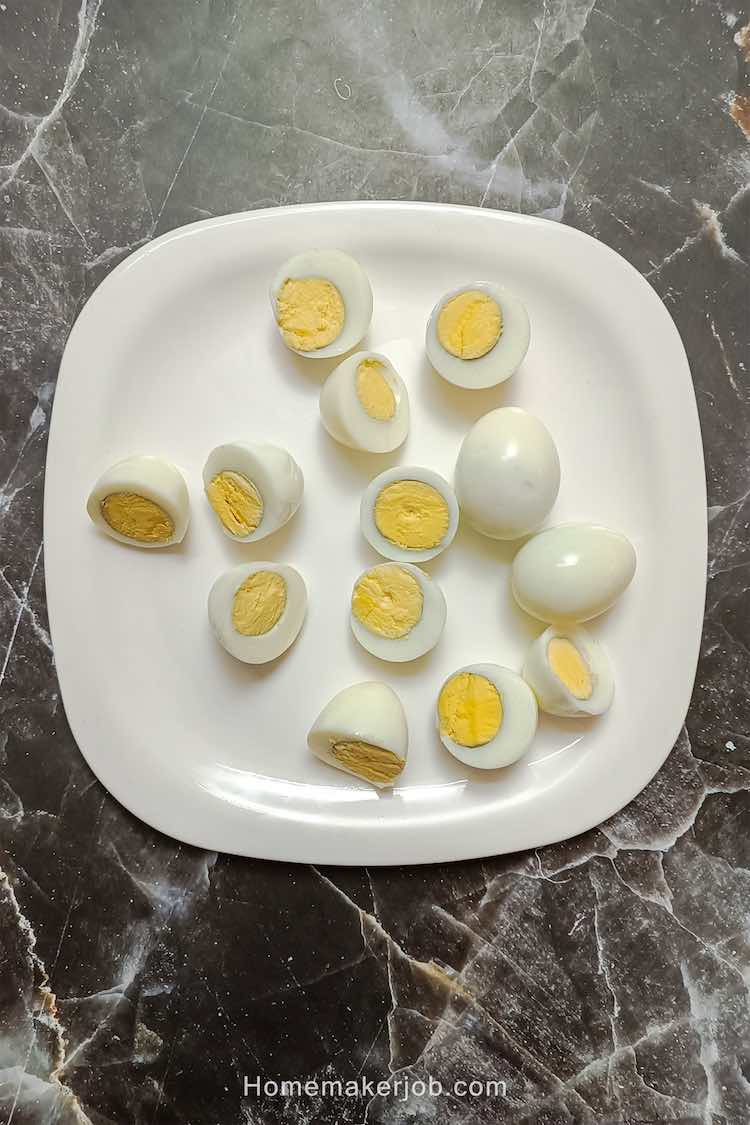 Top view photo of hard boiled eggs cut in half and placed in a white dish on a table, to make old-fashioned curried eggs recipe by homemakerjob.com