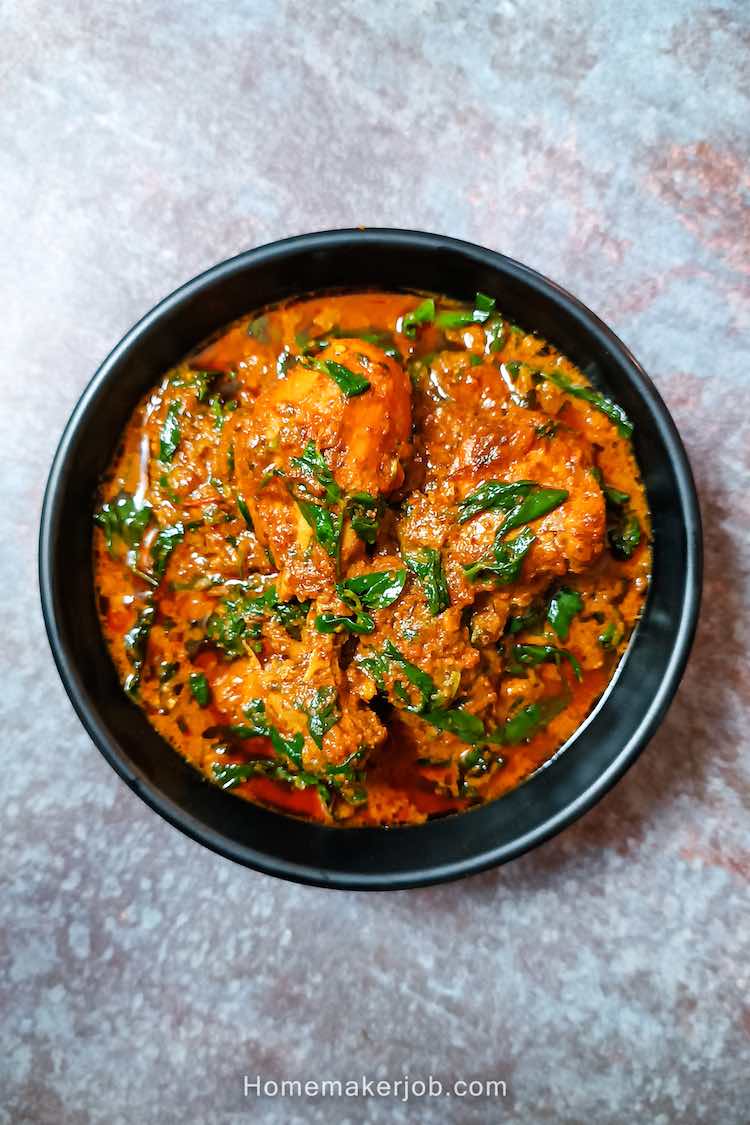 Methi chicken curry served hot in a black bowl on a table by homemakerjob