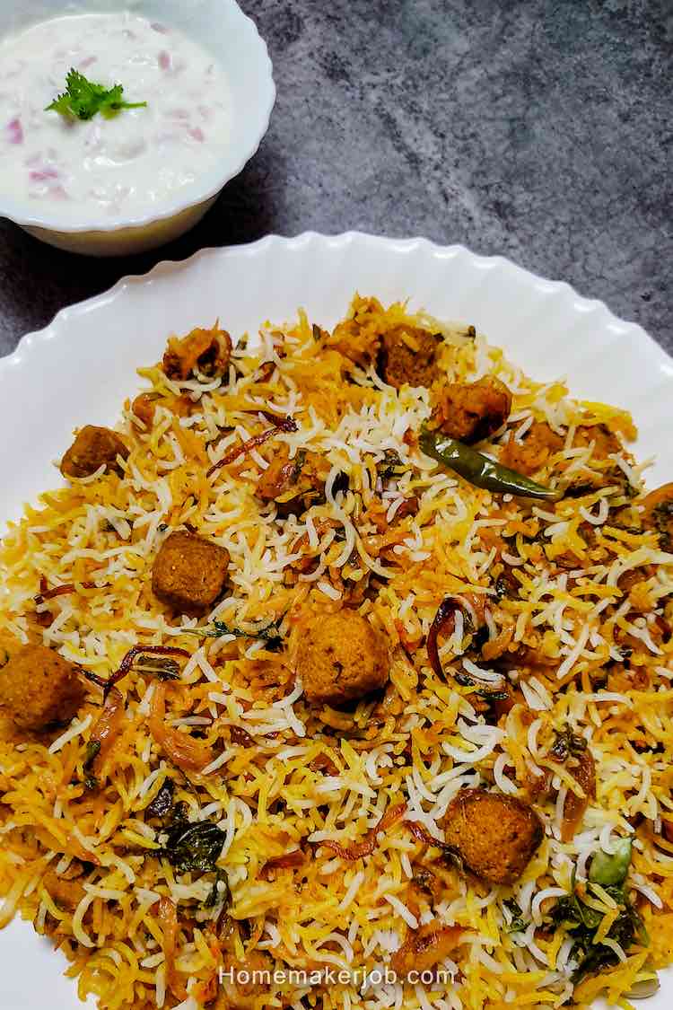 Soya bean chunks veg biryani served hot in a white plate with onion raita in a small bowl as a side dish, a recipe by homemakerjob.com