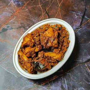 Top view photo of chicken chukka dry masala gravy in a white bowl, decorated with curry leaves and green chilies beside the bowl on a table, a recipe by homemakerjob.com