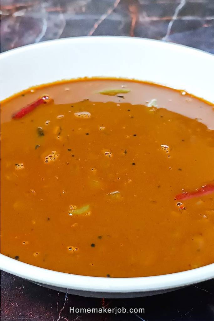 A top side view close-up photo of Ulava charu a.k.a. horse gram or kollu lentil rasam soup in a white bowl, a recipe by homemakerjob.com