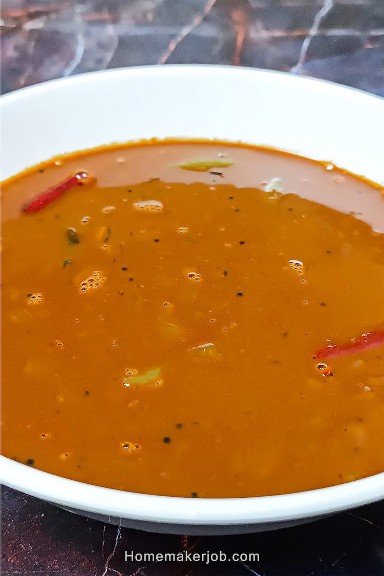 A top side view close-up photo of Ulava charu a.k.a. horse gram or kollu lentil rasam soup in a white bowl, a recipe by homemakerjob.com