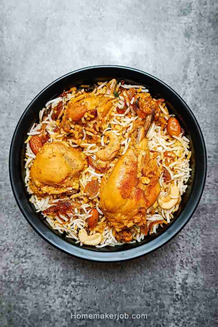 Top view photo of chicken mughlai biryani in a black bowl on a table, a recipe by homemakerjob.com